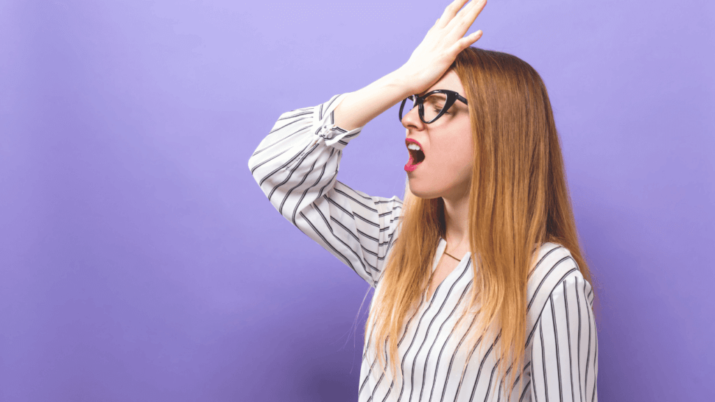 A woman slapping her forehead because she made mistakes in her video that is costing her views