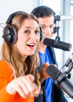 A man and woman speaking into microphones to represent having a guest on your live videos
