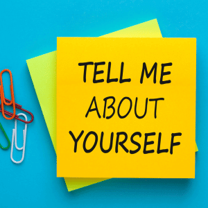 Tell me about yourself written on a yellow post-it note on a blue background